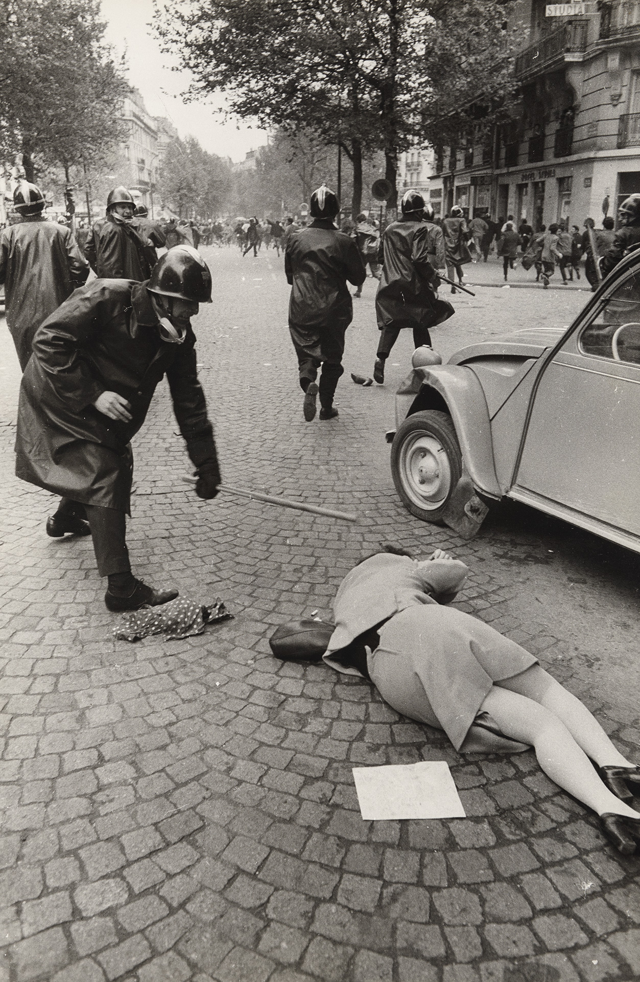 Gilles Caron, Premiers affrontements : CRS frappant une jeune femme à terre, Paris, 1968.