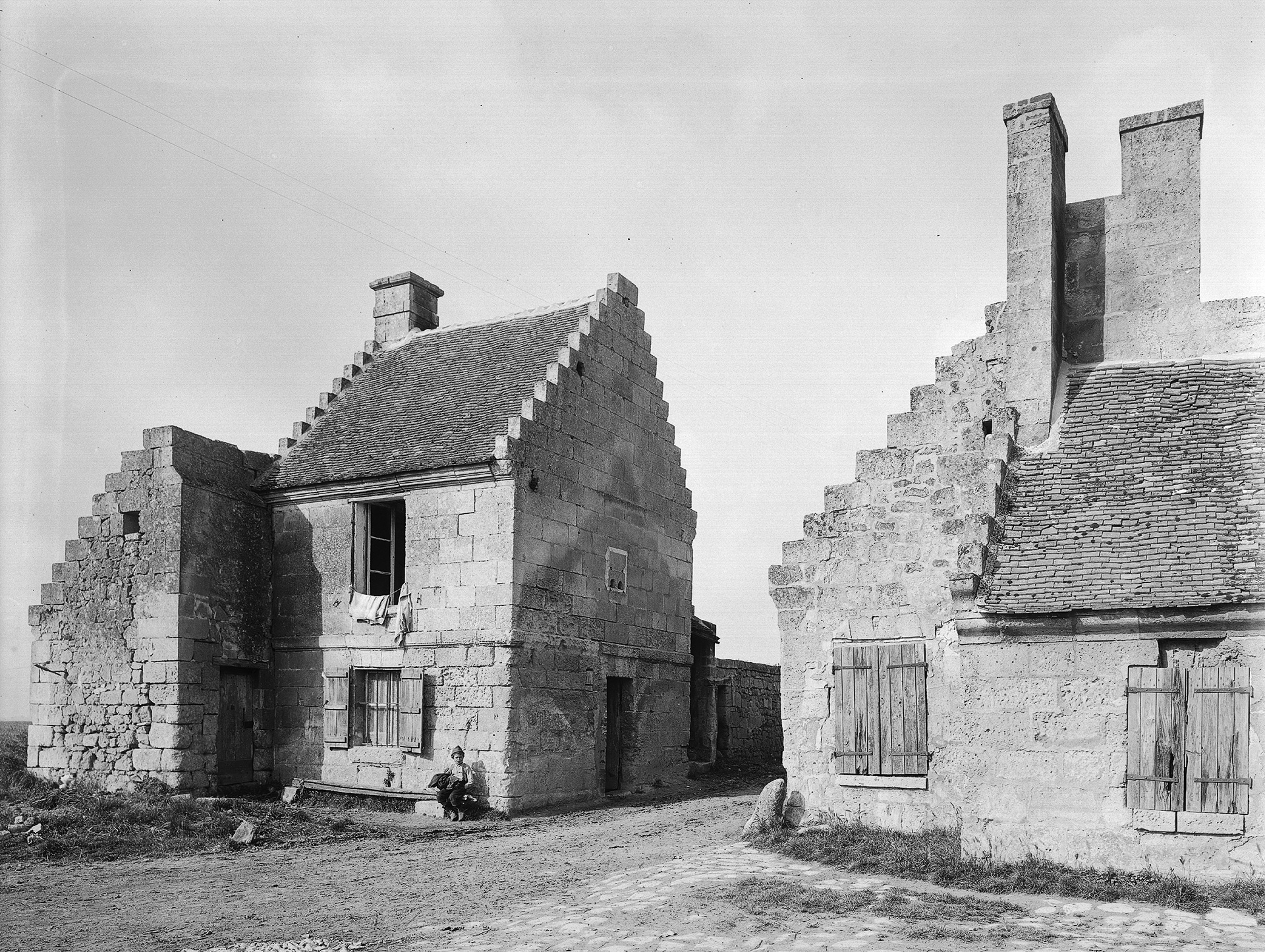 Photographie en noir et blanc. Deux petites maisons très anciennes.