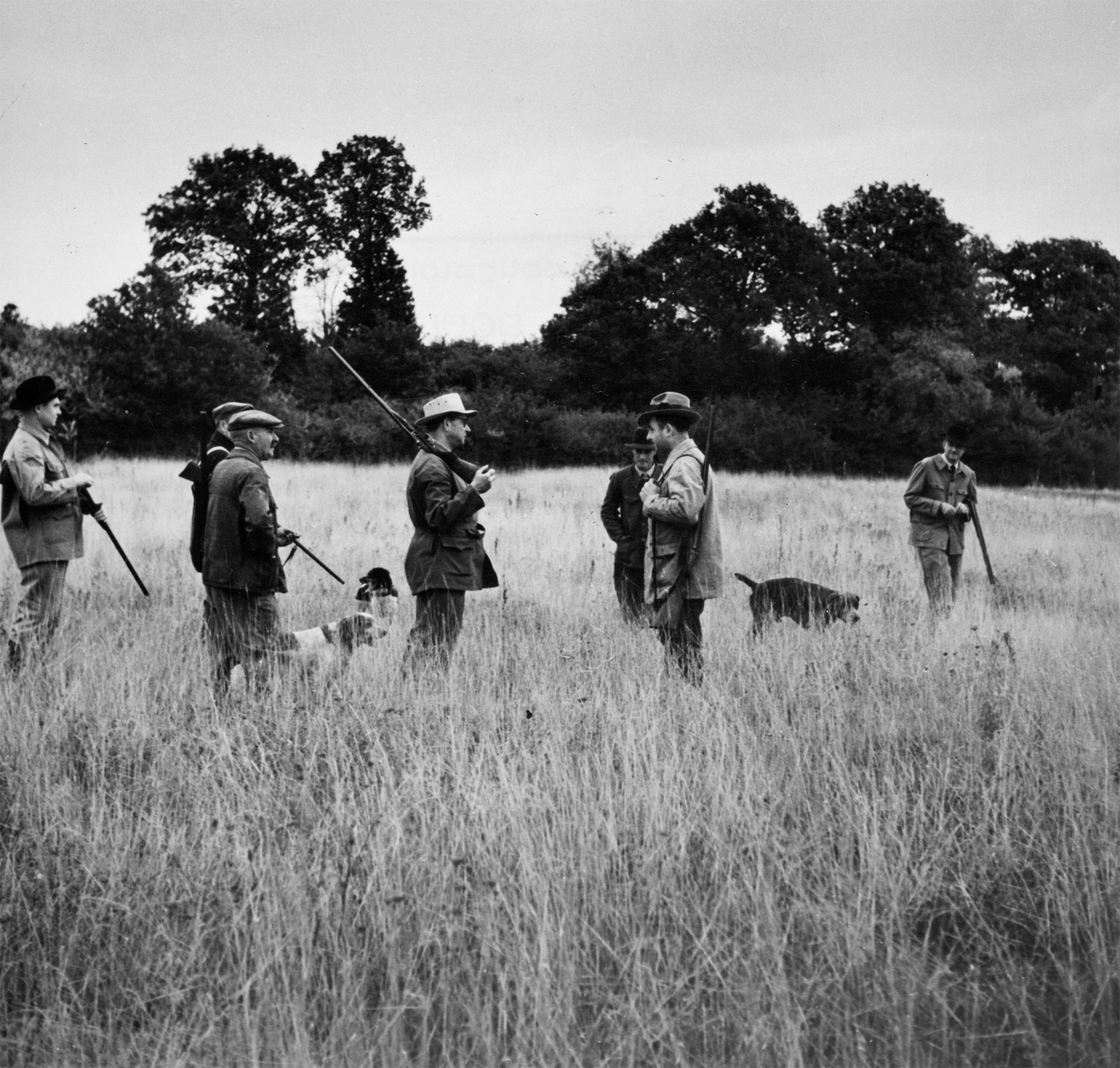 Groupe de chasseurs discutant dans un pré.