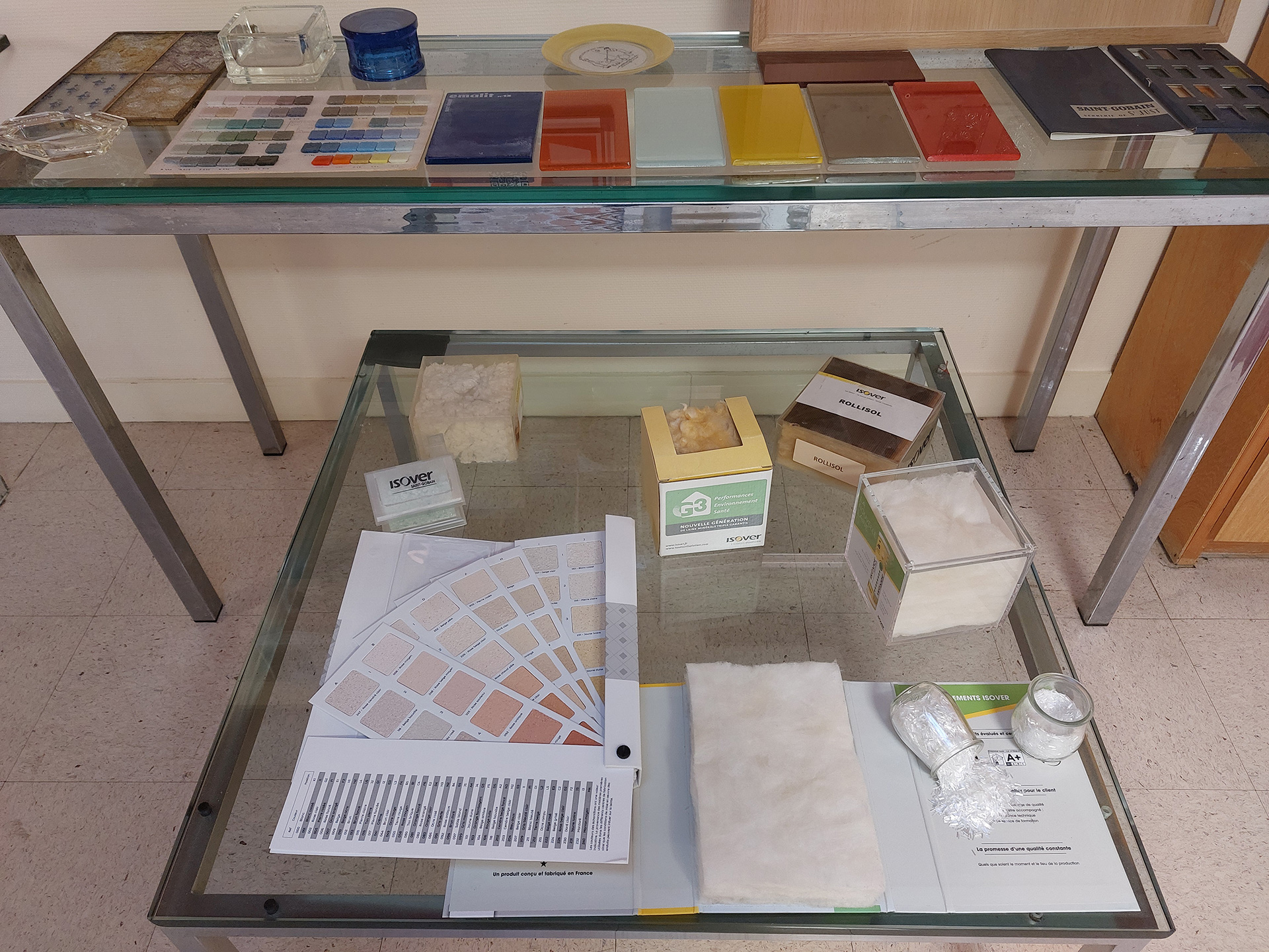 Section présentant les échantillons de l’activité renforcement : bobines de ruban et de fils de fibre de verre de marque Vetrotex, bandes FibaTape en maille de fibre de verre pour le renforcement des joints Adfors, et revêtements muraux décoratifs Novelio en fibre de verre.  En arrière-plan, ensemble de moulages en verre, XXe s.