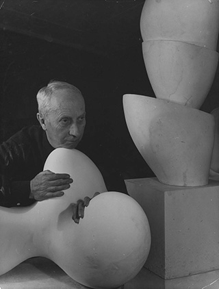 Denise Colomb, Arp ; [ Jean Arp, de trois-quarts, le menton appuyé sur une sculpture ], 1954