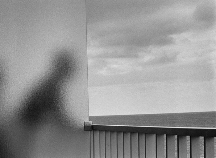 Un homme derrière un écran en verre dépoli regarde la mer depuis un bacon.