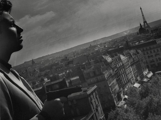 Michel Auclair de profile. Les toits de Paris en fonds.