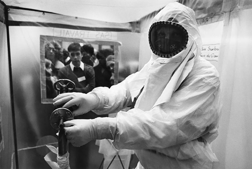 Une personne dans une combinaison de protection manipule un tableau de commande