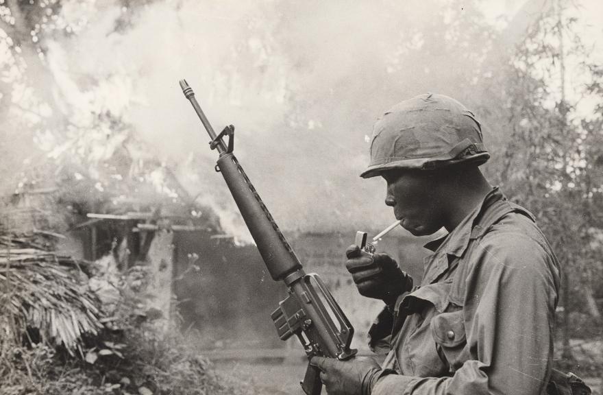 Gilles Caron, Guerre du Vietnam, opération Pershing, soldat américain allumant une cigarette devant un village incendié, 1967