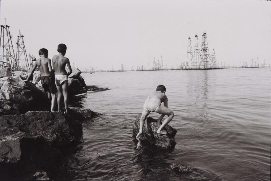Stanley Greene, Enfants jouant dans les eaux de la mer Caspienne, non loin des plateformes pétrolières de Bakou (Azerbaïdjan), 1998 