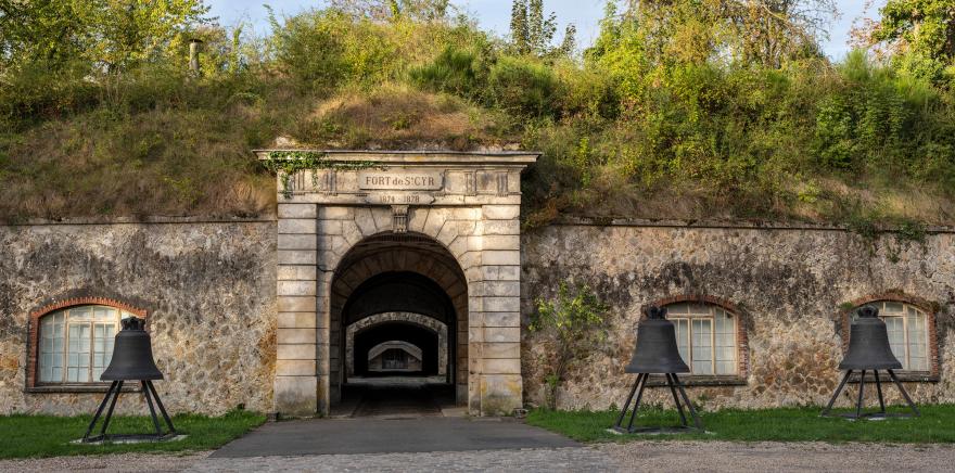 Photo en couleur du fort de Saint-Cyr. Trois cloche de Notre-Dame de Paris encadrent l'entrée du premier tunnel.