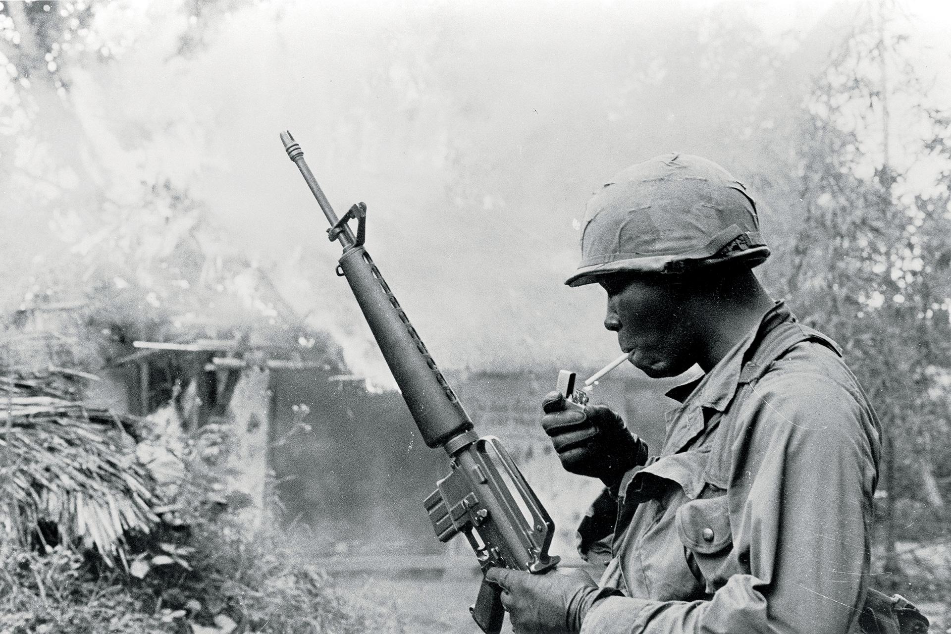 Gilles Caron, Guerre du Vietnam, opération Pershing, soldat américain allumant une cigarette devant un village incendié, décembre 1967