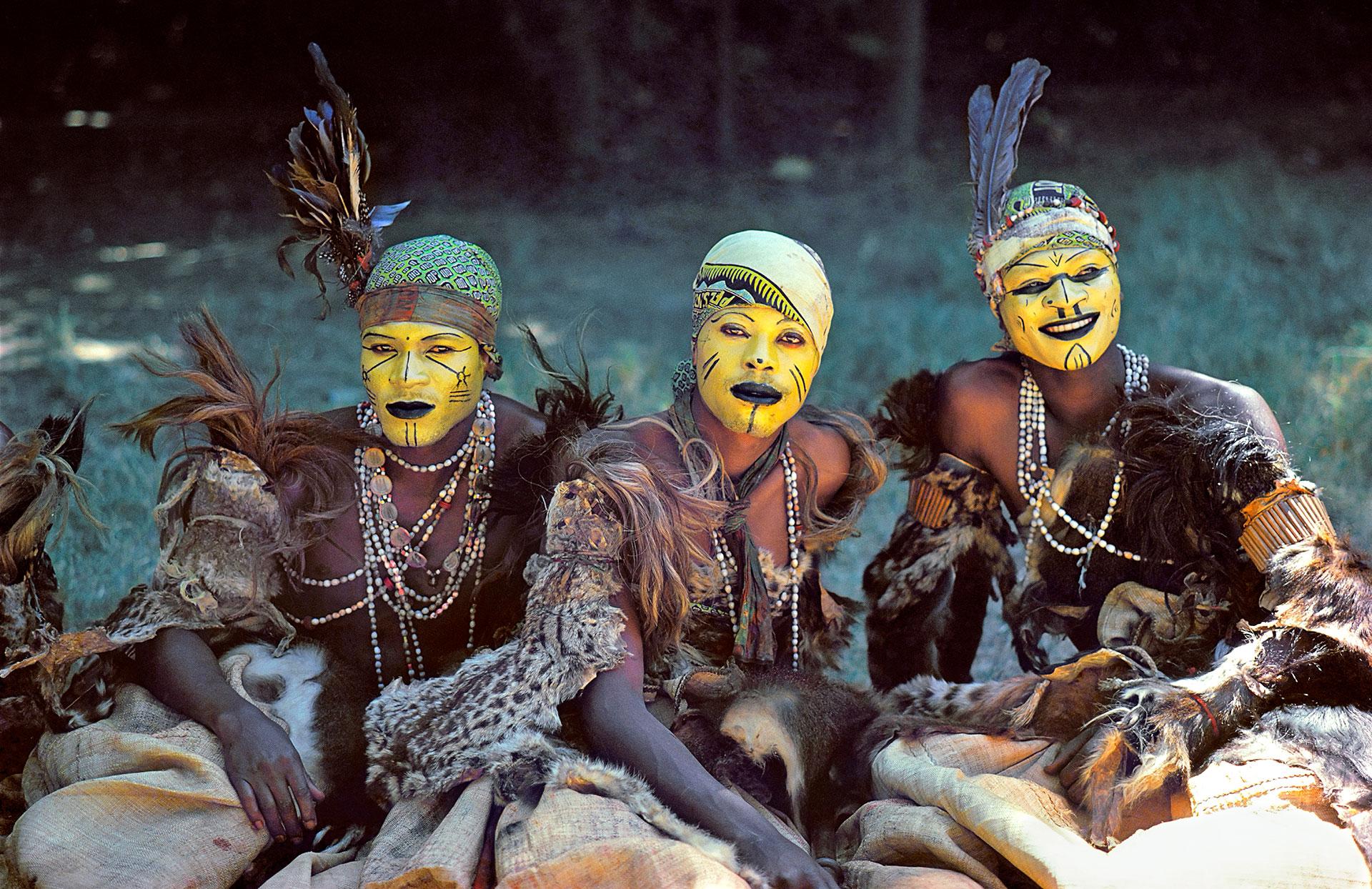 Trois danseurs traditionnel congolais assis à l'ombre.