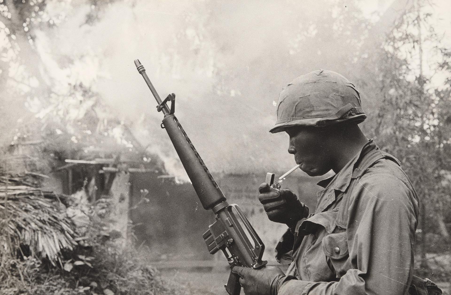 Gilles Caron, Guerre du Vietnam, opération Pershing, soldat américain allumant une cigarette devant un village incendié, 1967